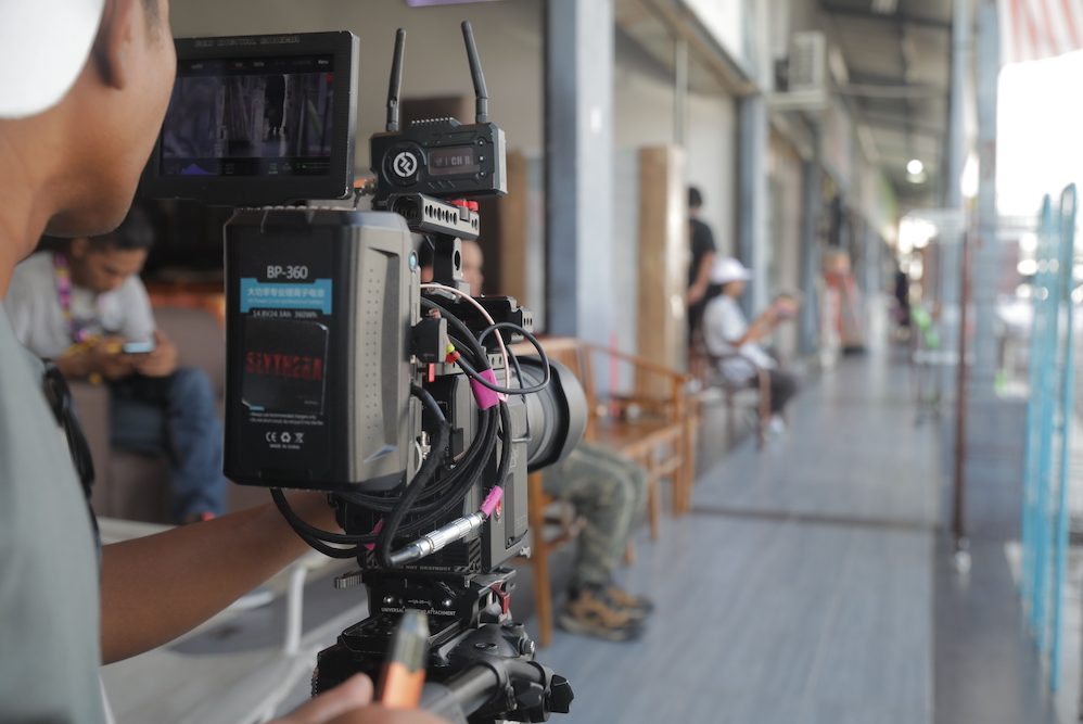 A professional video production camera setup owned by Zaramiz Sdn Bhd on a movie set or hallway corridor, capturing behind-the-scenes cinematography layout.