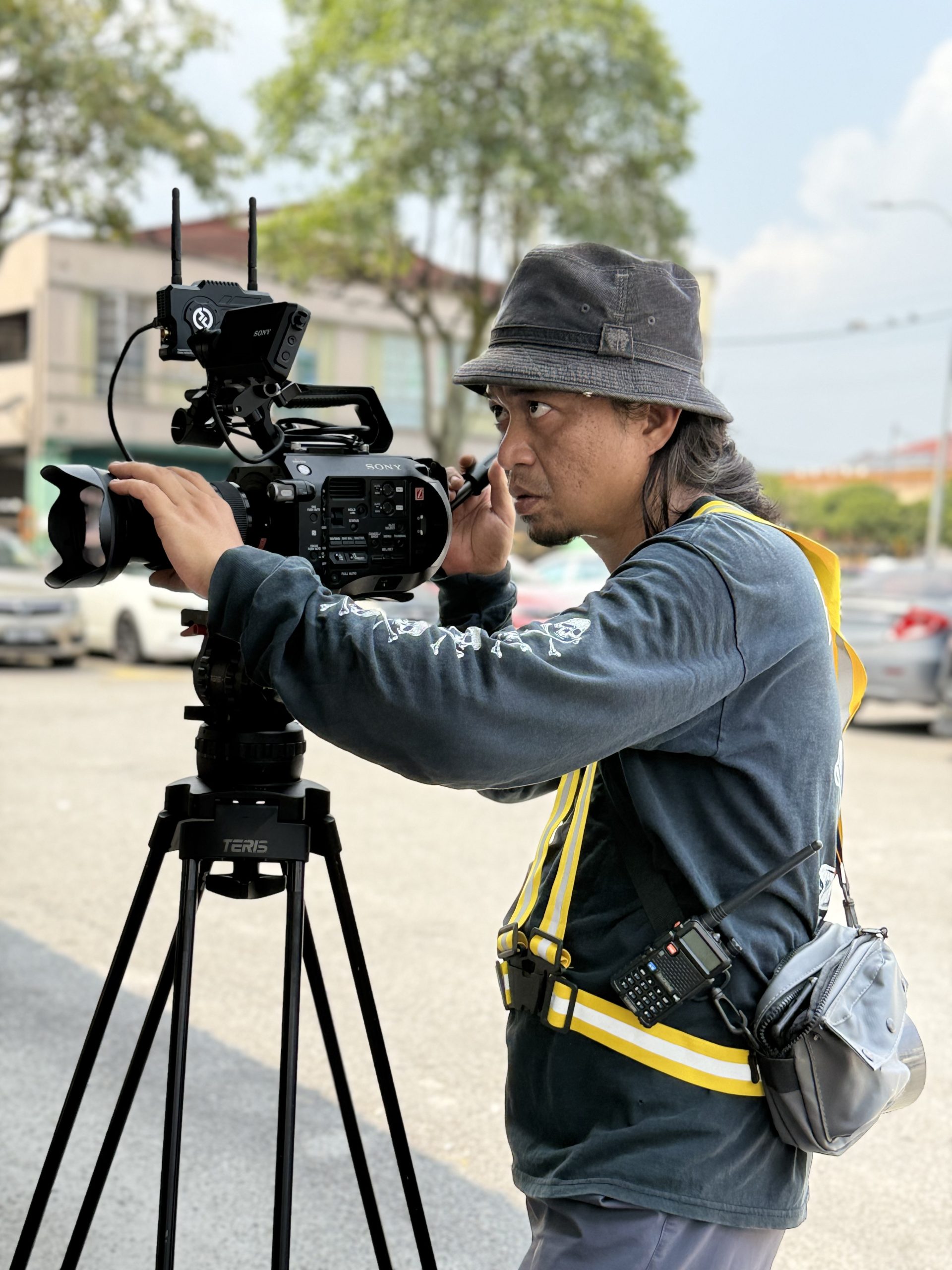 Profile photo of Awan Shuib, Director Editor at Zaramiz Sdn Bhd, captured behind the scenes operating a professional video camera on a tripod.